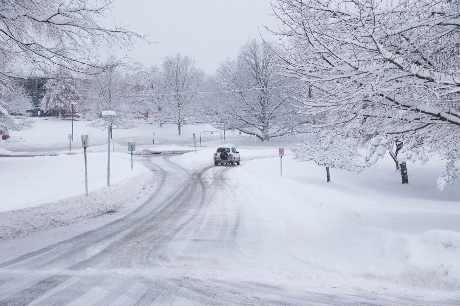 A car slowly driving on snowy road in winter